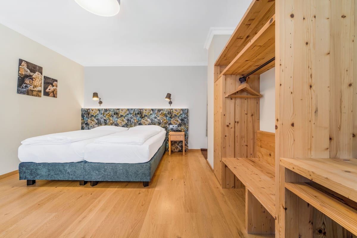 Quarto com cama, um banco de madeira e parede com padrão floral.