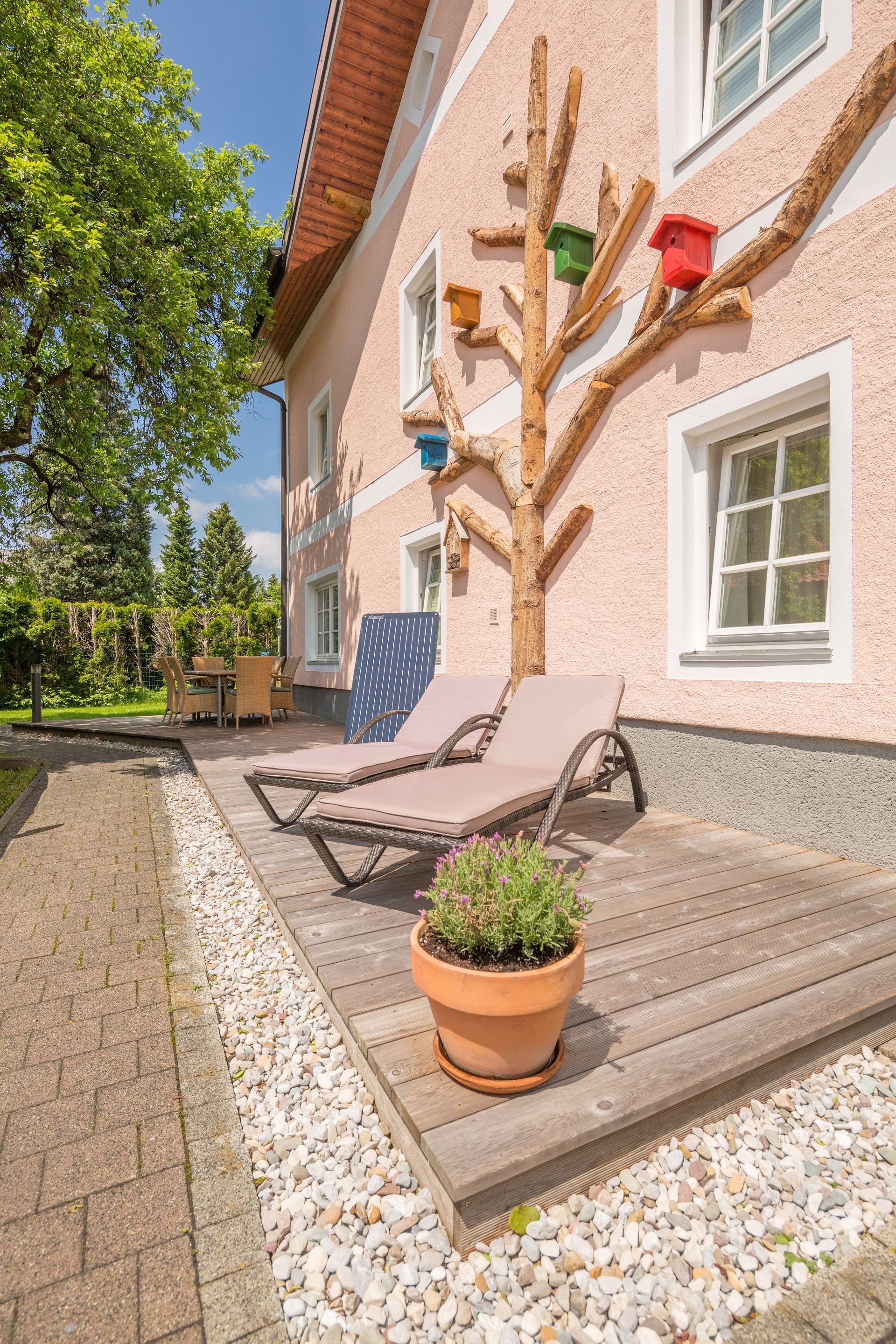 A building with a wooden deck, outdoor seating, and birdhouses on the wall.