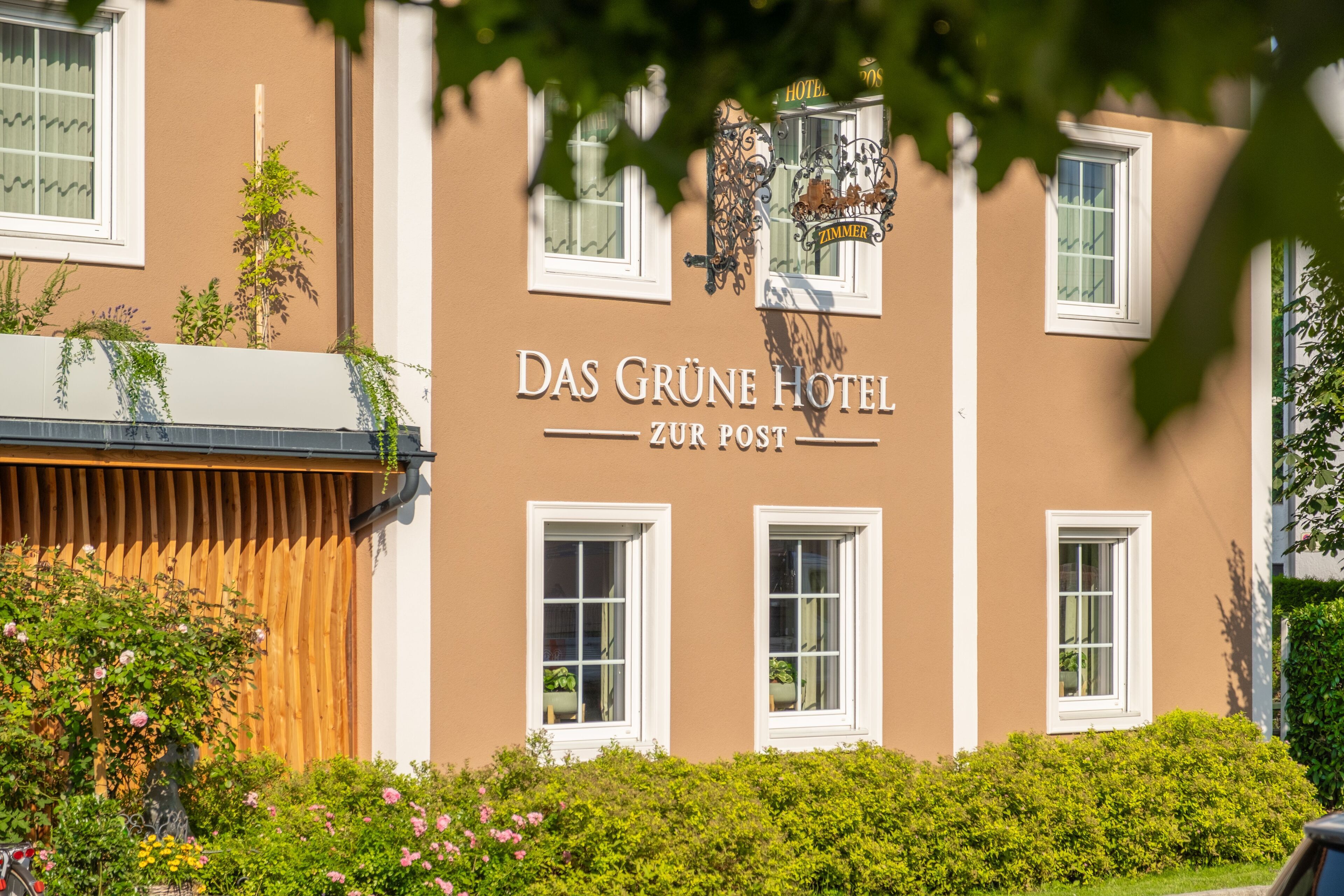 A hotel facade with the name 'Das Grüne Hotel' and 'Zur Post' signage.