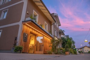 A hotel entrance with a wooden facade, a glass door, and a small outdoor seating area with plants. - Das Grüne Hotel zur Post (Salzburg)