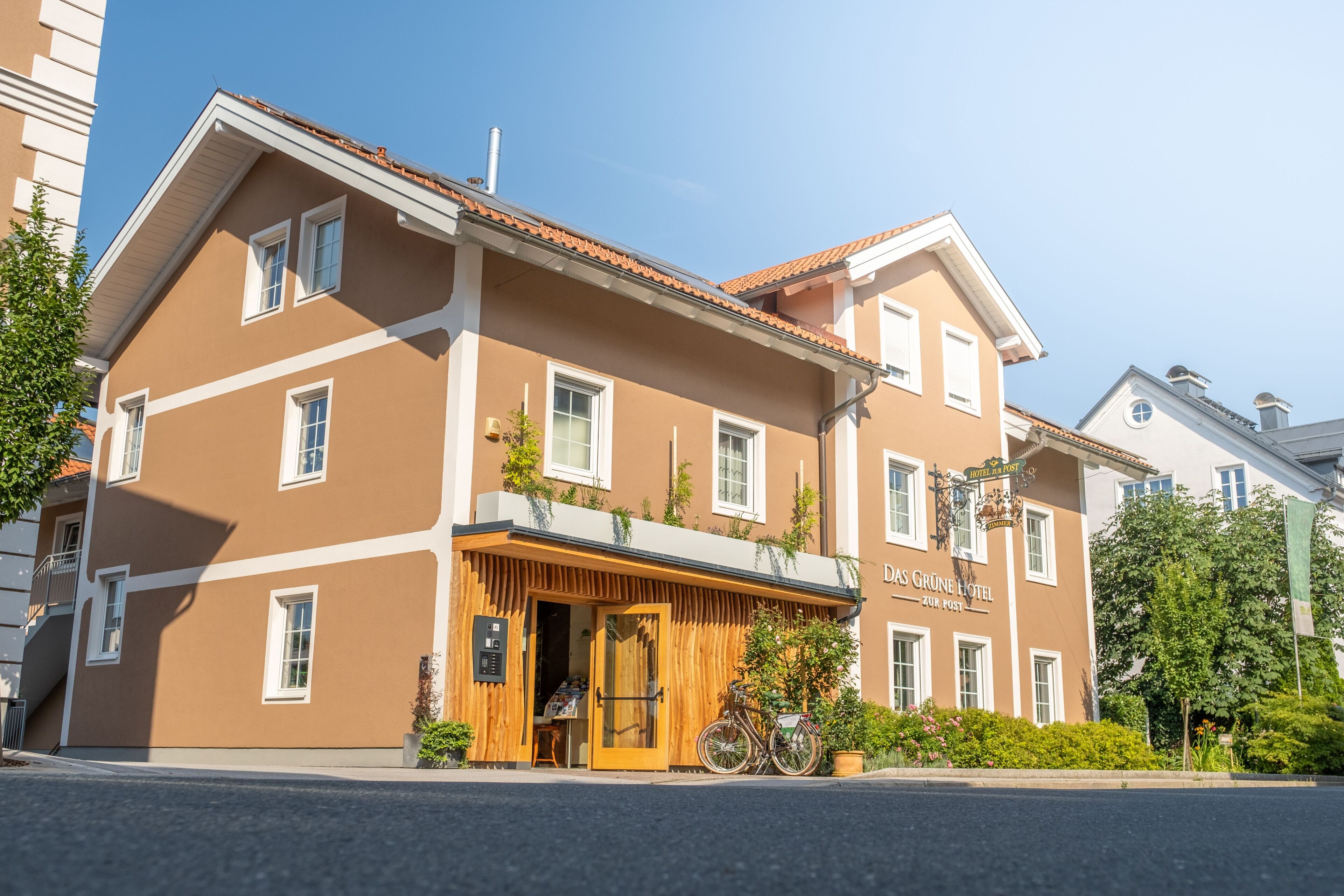 Un edificio di due piani con facciata marrone, ingresso in legno e un cartello con la scritta "Das Grüne Hotel".