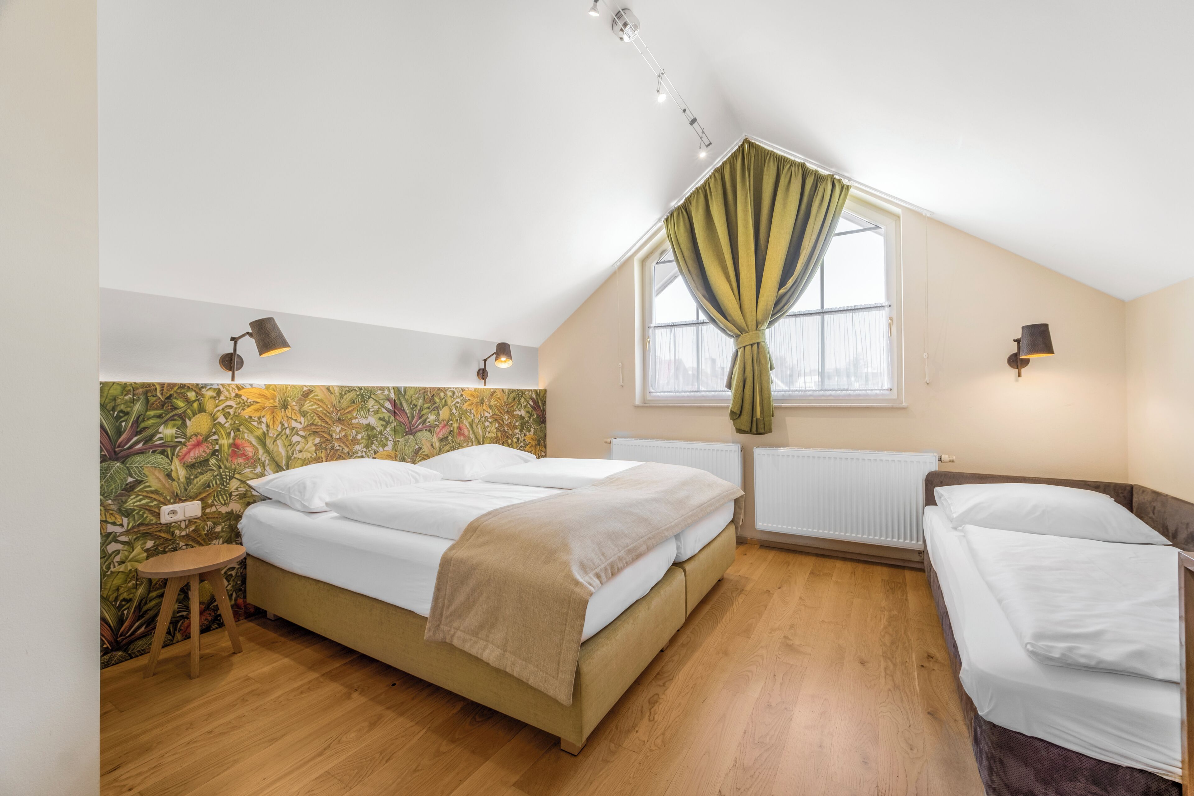 Una camera da letto con un letto, uno sgabello, un termosifone e una finestra con tende.