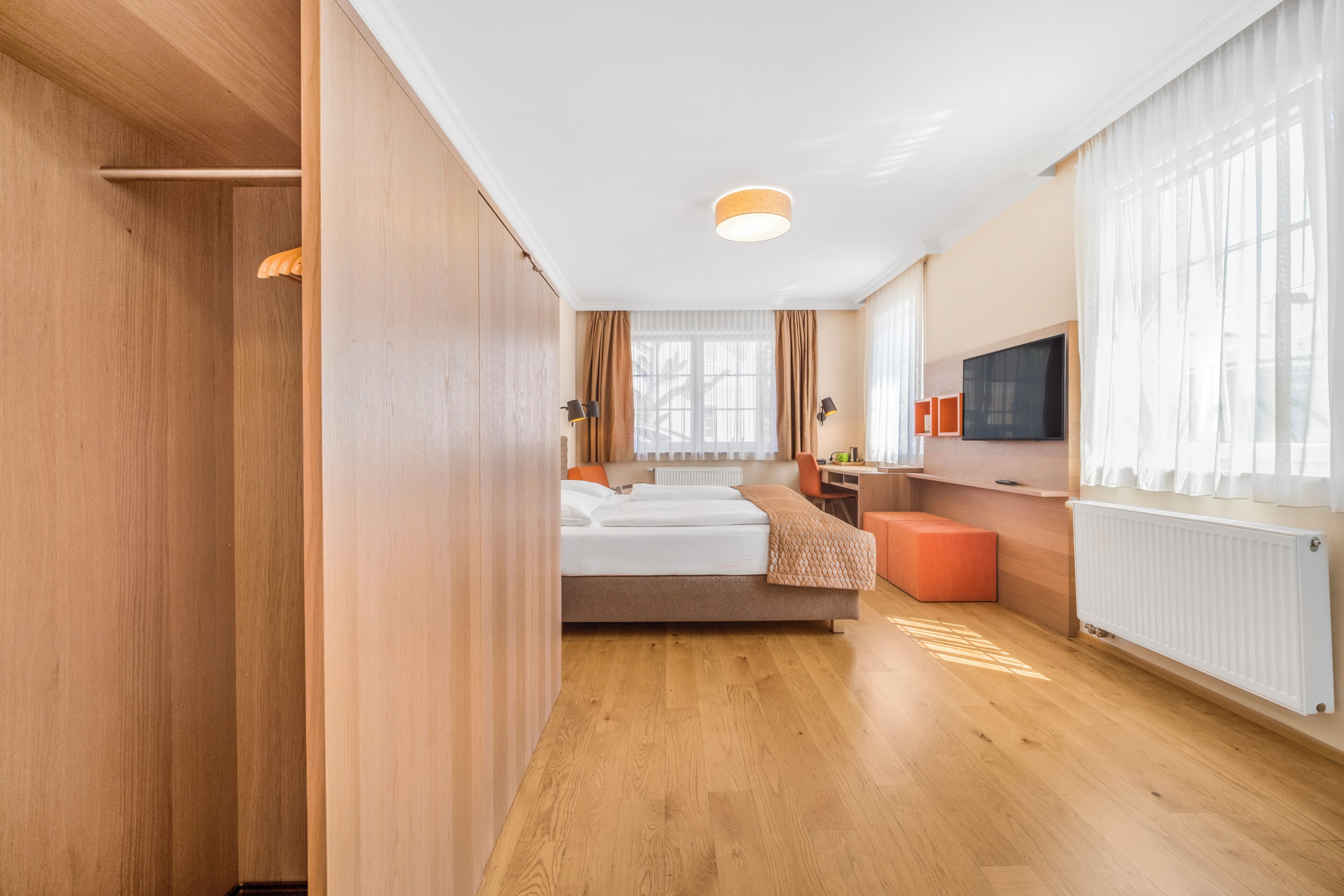 Une chambre d’hôtel avec un lit, un bureau, une télévision et une fenêtre avec des rideaux.