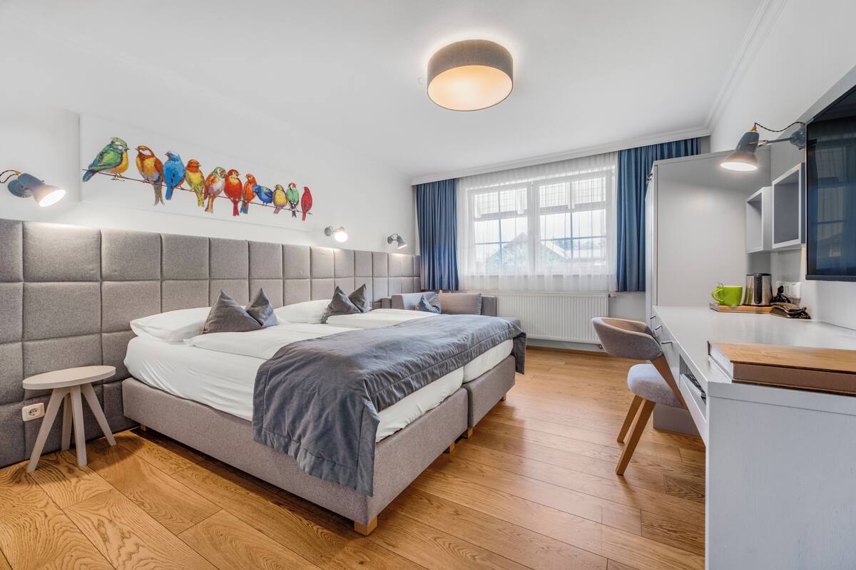 Quarto moderno com uma cama grande, uma escrivaninha e uma janela com cortinas.