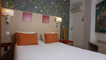 Una habitación de hotel con una cama grande, dos lámparas de pared, un escritorio pequeño y una silla.