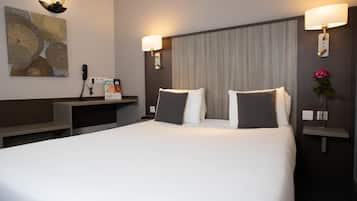 A hotel room with a large bed, two bedside lamps, a nightstand, a telephone, and a decorative wall piece.