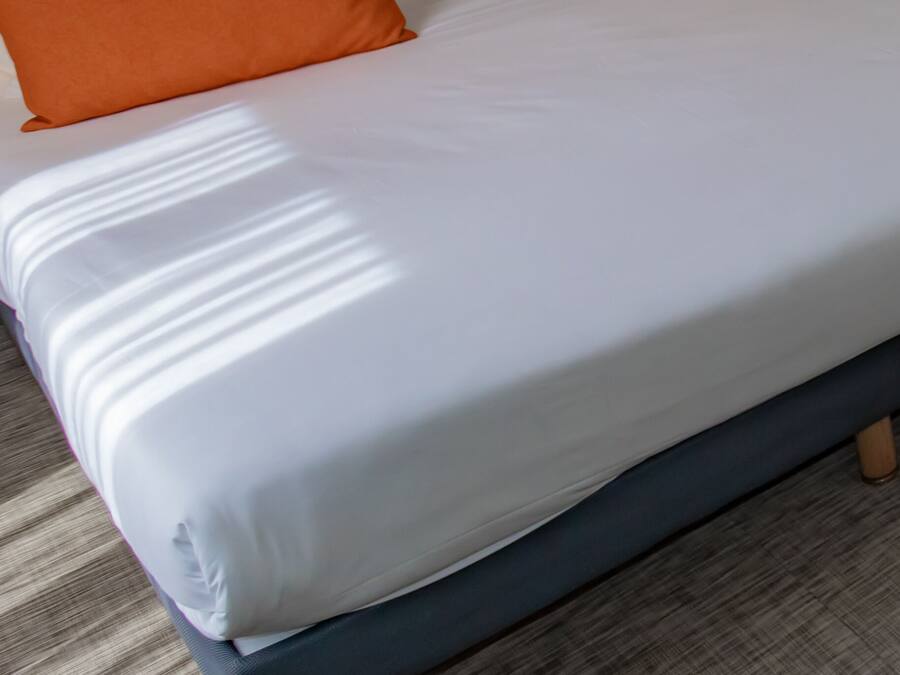 A bed with a quilted headboard, two pillows, and a wooden floor.
