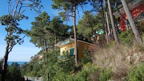 A coastal building with a stone wall and pine trees. - Resort La Francesca (Bonassola)