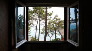 A window with a view of tall pine trees and a body of water. - Resort La Francesca (Bonassola)