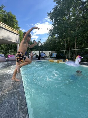 A person jumping into a swimming pool with a unicorn floatation device. - Hotel Obermayr (Ebenau)