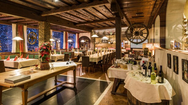 Un restaurante con vigas de madera, mesas dispuestas para comer y un gran adorno circular en la pared.
