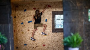 Una persona escalando una pared de madera con puntos de diferentes colores.