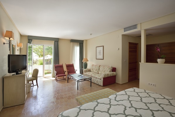 A hotel room with a television, a sofa, a chair, a small table, and a bed.