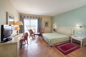 A hotel room with a bed, desk, TV, chairs, and a window with curtains.