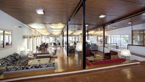 A spacious lobby with wooden flooring, multiple seating areas, and large windows offering views of the outdoors. - Parador de Ayamonte (Ayamonte)