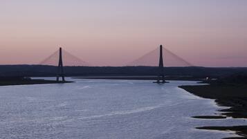 A large suspension bridge over a calm river at dusk.