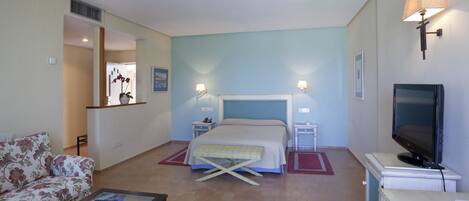 Una habitación de hotel con cama, televisión, sofá y una mesita.