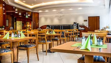 A restaurant with wooden tables and chairs, a coffee machine, and a chalkboard menu.