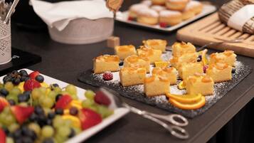 A dessert table with various pastries and fruit arrangements.