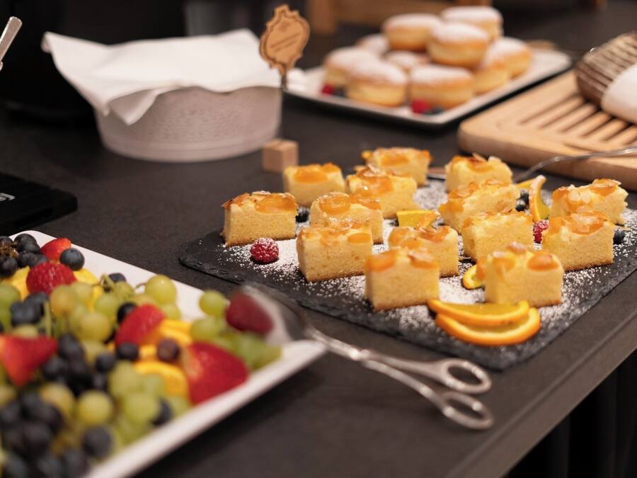A dessert table with various pastries and fruit arrangements.