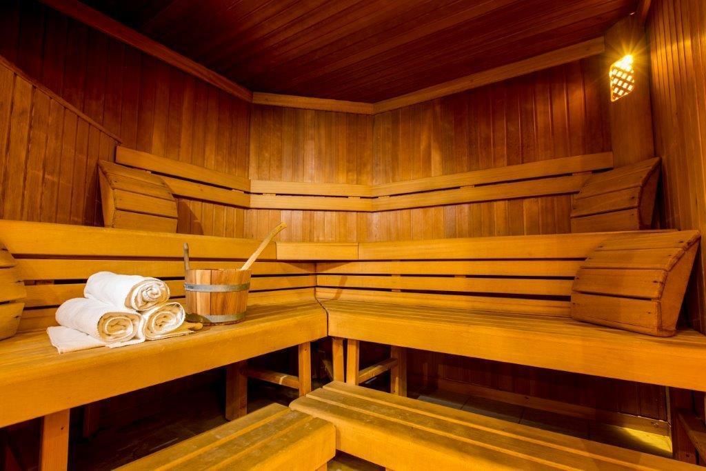 Sauna, jossa on puiset lauteet, pyyhkeet ja ämpäri.