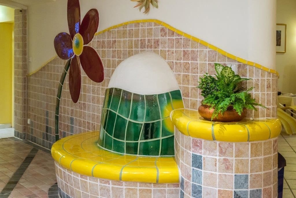 A tiled wall with a large flower decoration and a potted plant.