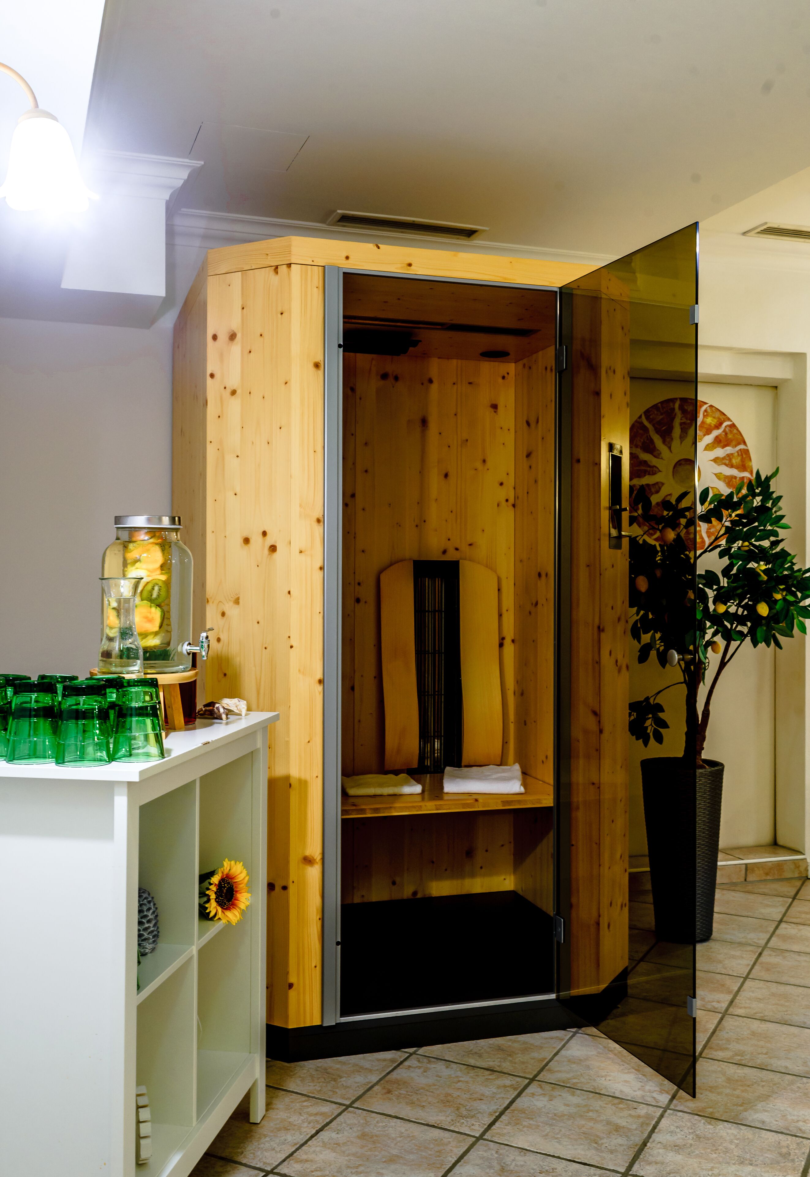 A room with a wooden cabinet, a glass jar with a drink, and a potted plant.
