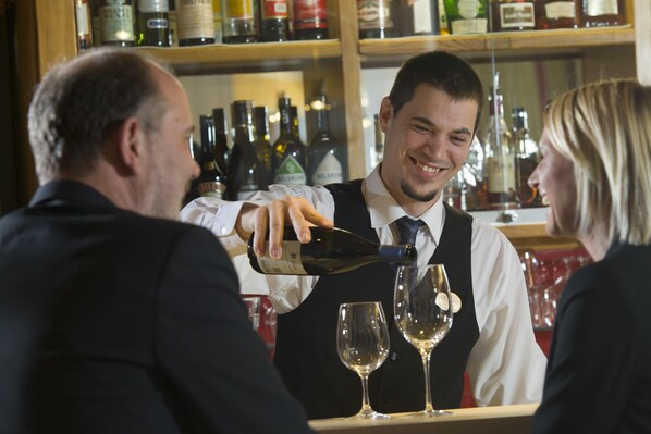 A bartender pouring a drink into a wine glass at a bar. - SPA Hotel Erzherzog Johann (Bad Aussee)