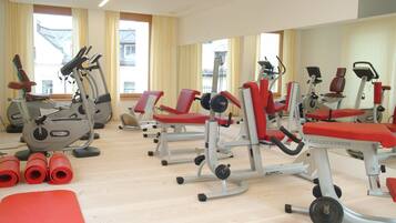 Un gimnasio con equipo de ejercicio, incluyendo cintas de correr y máquinas de pesas, dispuestas en filas.