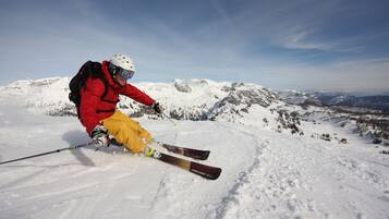 Een persoon skiënd op een besneeuwde berg met een heldere lucht.