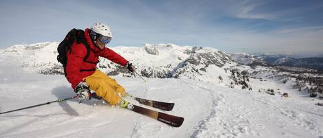 A person skiing on a snowy mountain with a clear sky.