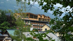A multi-story building with a wooden facade and large windows, surrounded by mountains and trees.