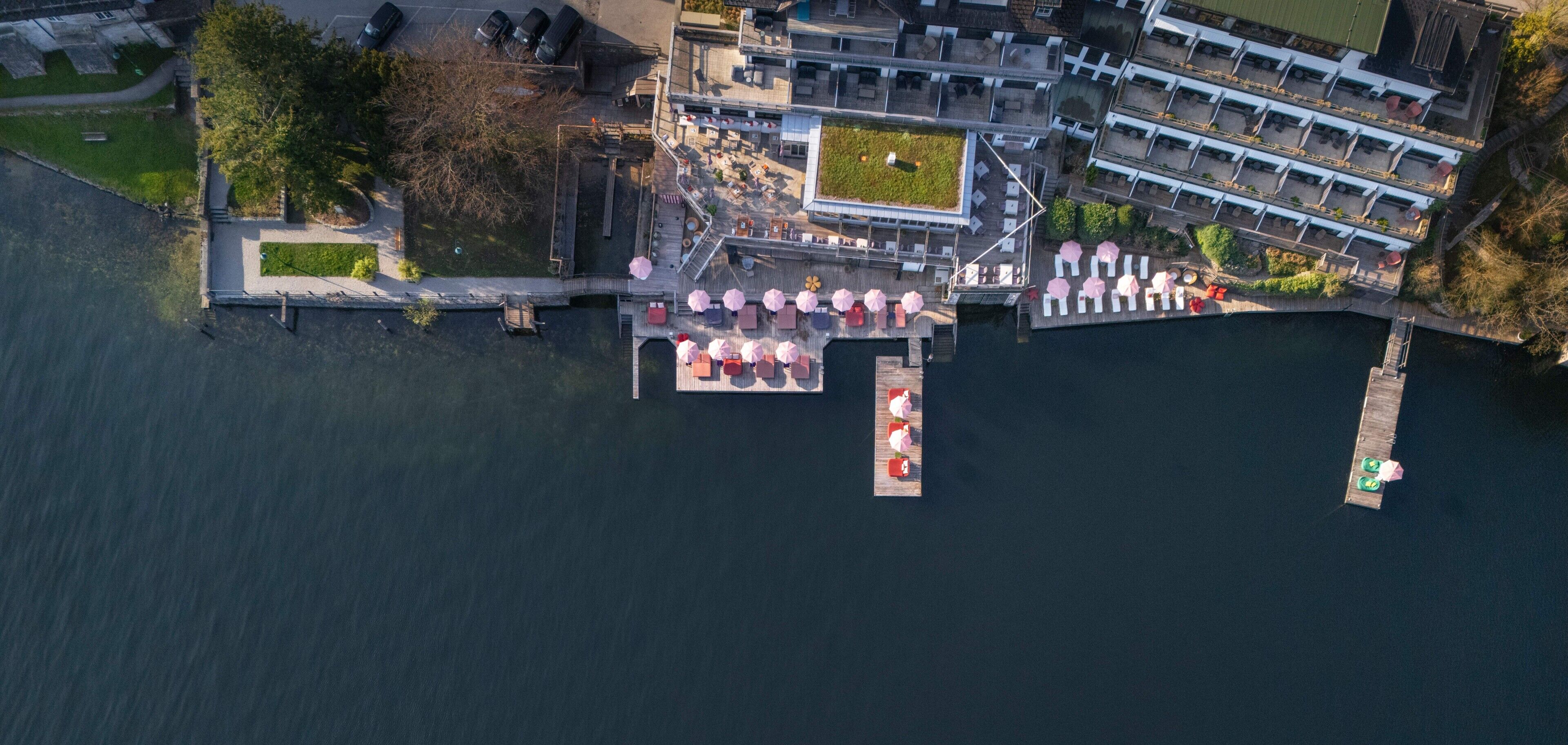 Vista aérea de una propiedad frente al agua con muelle, zona de estar al aire libre y un edificio de varios niveles.