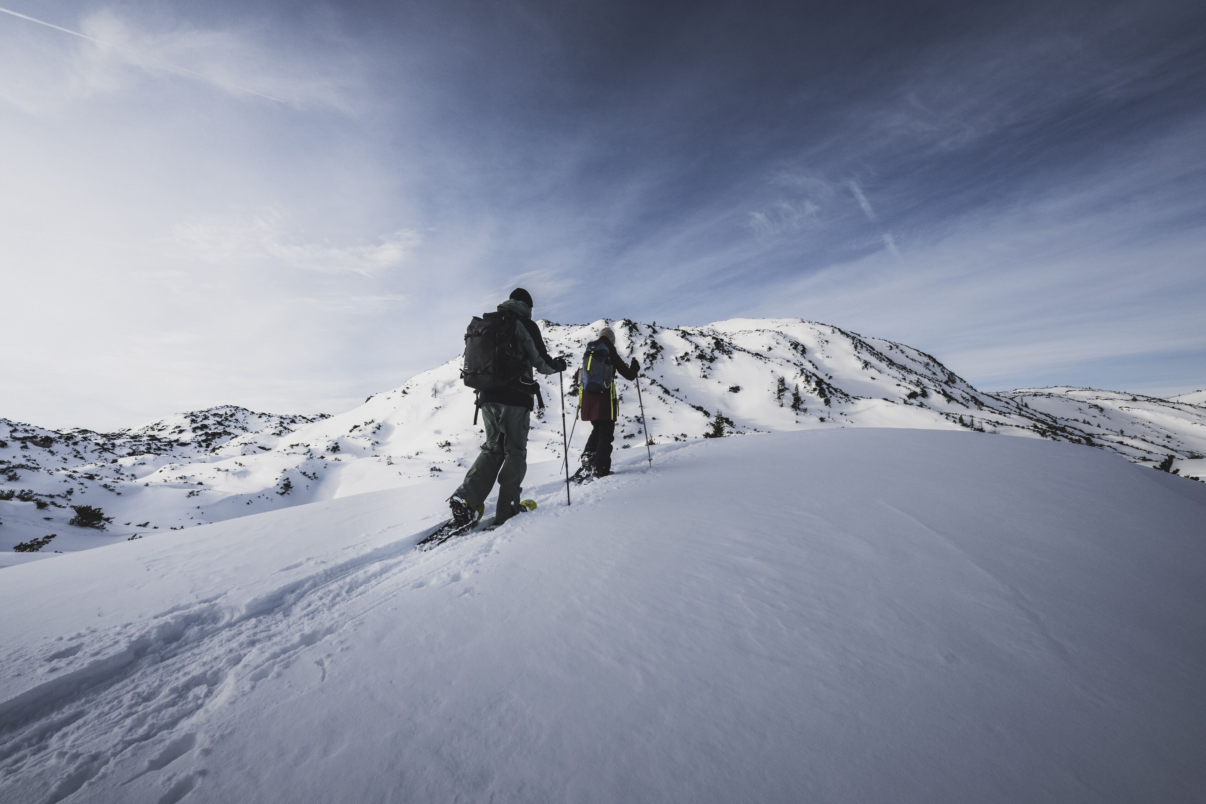 A snowy mountain landscape with two hikers.
