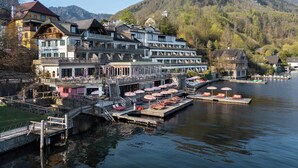 A lakeside hotel with multiple balconies, a dock with boats, and a mountainous backdrop. - Das Traunsee (Traunkirchen)