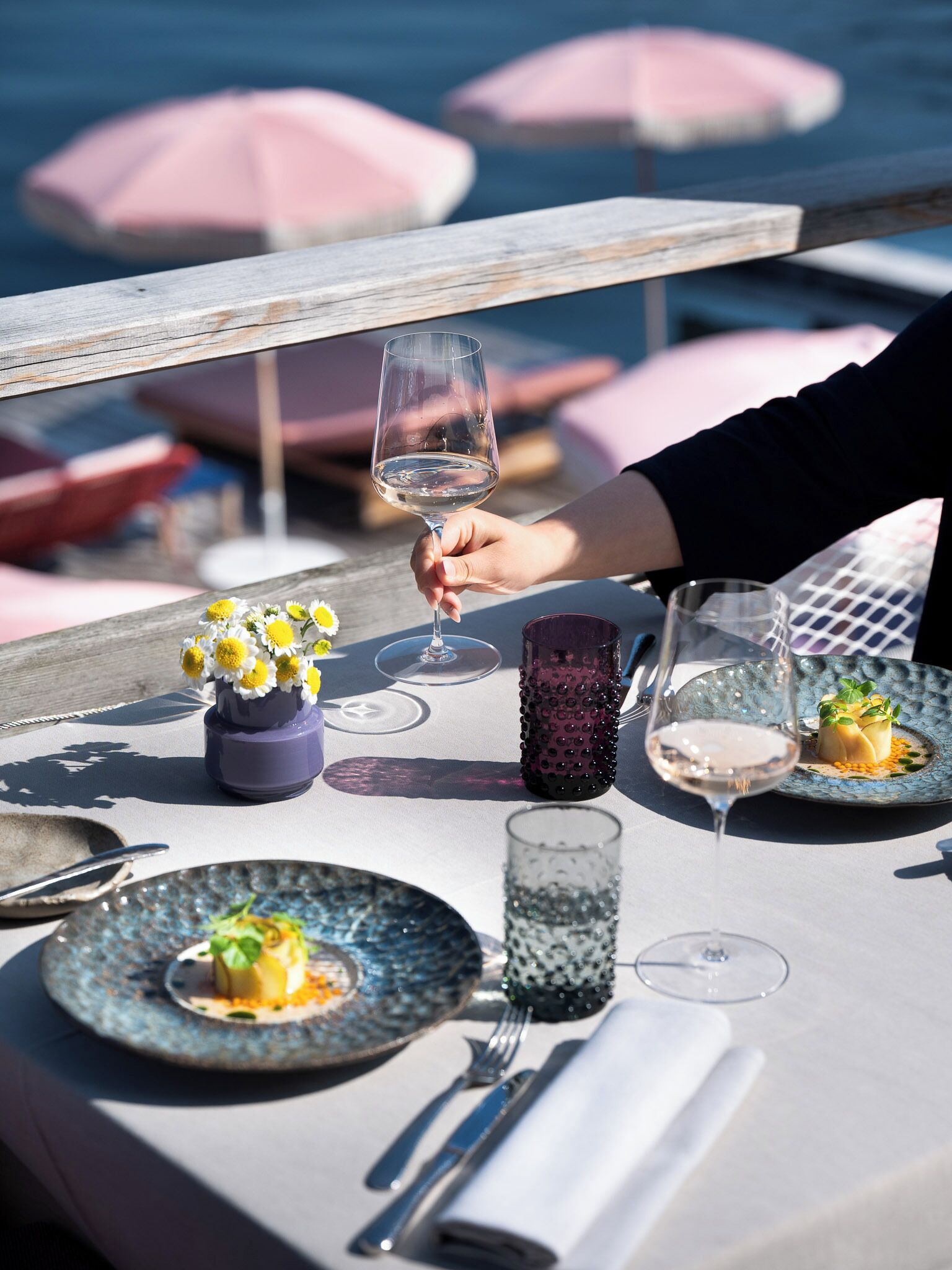 A dining table with plates of food, a wine glass, and a vase of flowers.