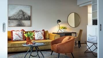 A living room with a sofa, armchair, coffee table, lamp, and a painting on the wall.