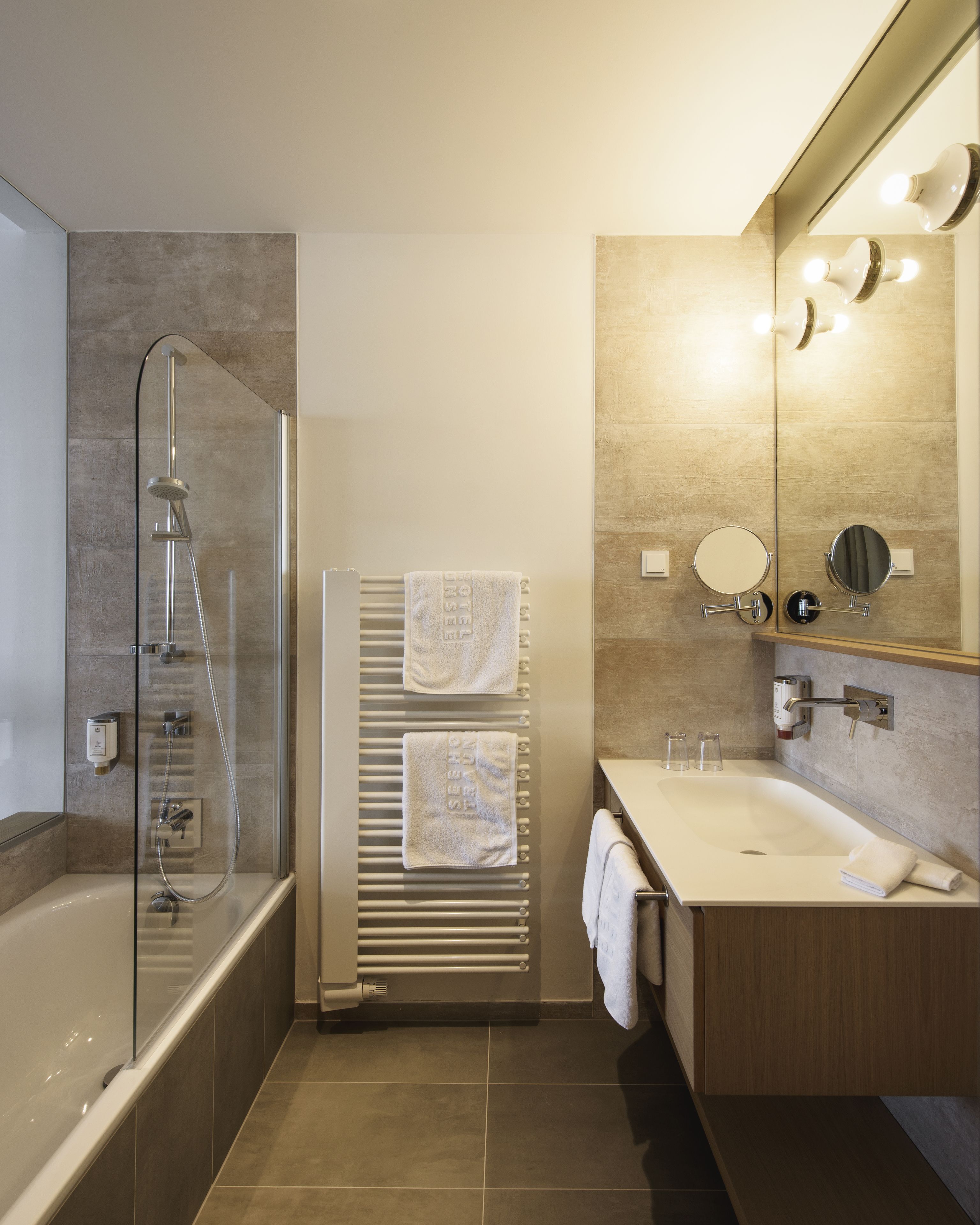 Un baño moderno con ducha envuelta en vidrio, lavamanos integrado y un espejo grande.