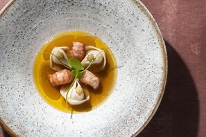 A ceramic plate with a dish containing dumplings in a yellow sauce, garnished with greens.