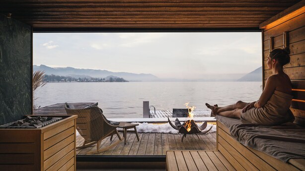 A wooden deck with a fire pit, seating, and a view of a lake. - Das Traunsee (Traunkirchen)