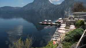 A lakeside dock with lounge chairs and umbrellas, a wooden deck, and mountains in the background. - Das Traunsee (Traunkirchen)