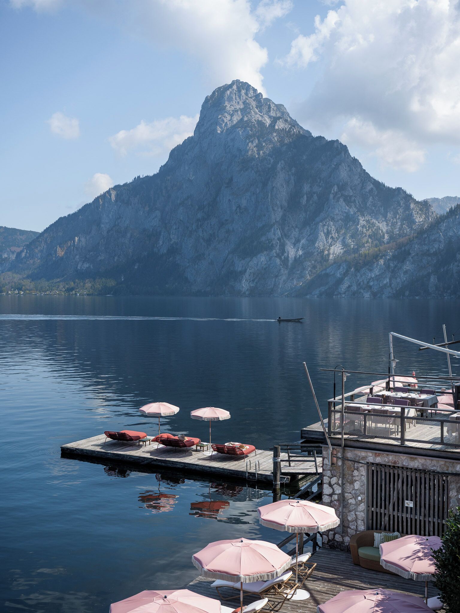 A lakeside dock with outdoor seating and a mountain backdrop.