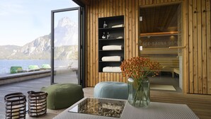A wooden interior with a sauna, a glass table, and a view of the sea. - Das Traunsee (Traunkirchen)