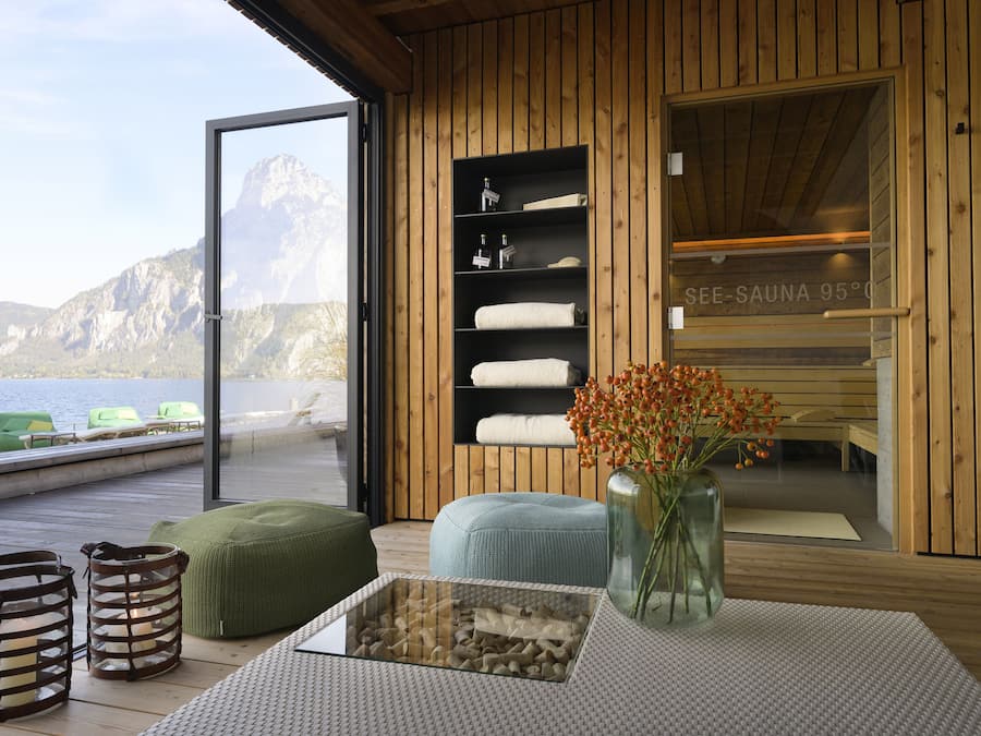 Un interior de madera con sauna, una mesa de vidrio y vista al mar.