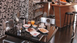 Un comptoir-buffet où l’on peut prendre le petit-déjeuner, avec une variété d’aliments et de boissons, une machine à café et un ordinateur portable posé sur le comptoir.