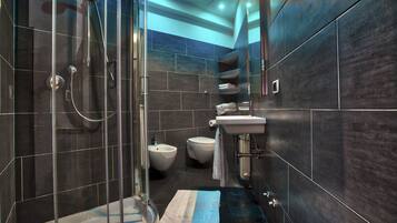 Un baño moderno con ducha de vidrio, un bidé, inodoro y lavamanos.