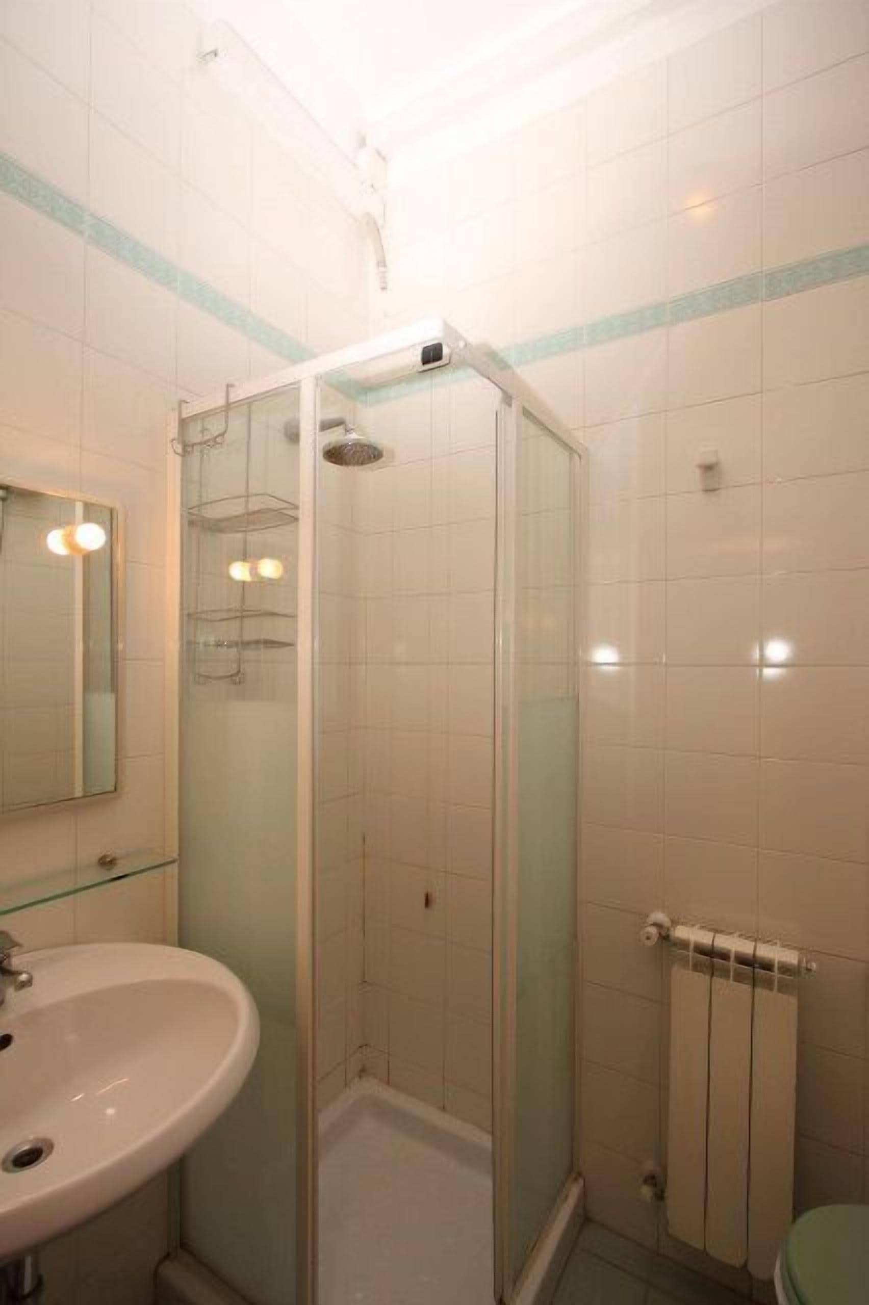 A bathroom with a glass-enclosed shower, a sink, and a toilet.