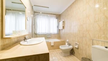 Un baño moderno con un espejo grande, un lavabo, un bidé y un inodoro.