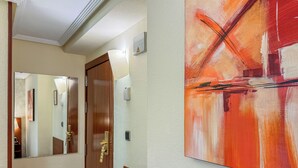Un pasillo con una puerta de madera, un espejo y un cuadro en la pared.