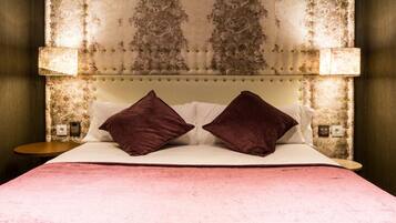A bed with a tufted headboard, two pillows, and a pink bedspread.